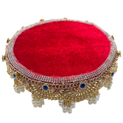 Decorative red cushion with gold and blue embellishments on a white background